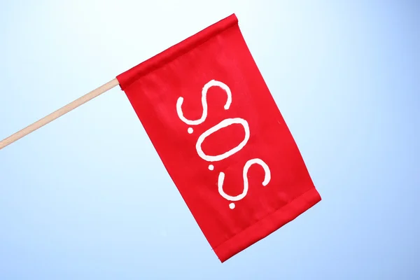 SOS-signaal geschreven op rode doek op blauwe achtergrond — Stockfoto