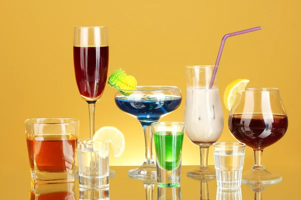 Olika alkoholhaltiga drycker på gul bakgrund — Stockfoto