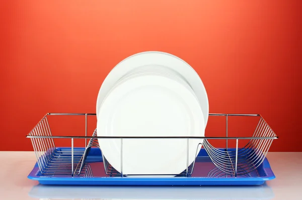 Pratos limpos em stand no fundo vermelho — Fotografia de Stock