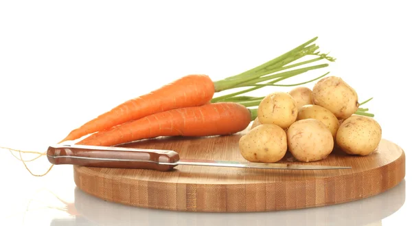 Papas jóvenes y zanahorias en una tabla de cortar con cuchillo aislado en blanco — Foto de Stock