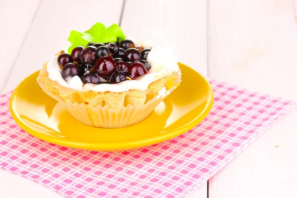 Sweet cake with berries on saucer on wooden background — Stock Photo, Image