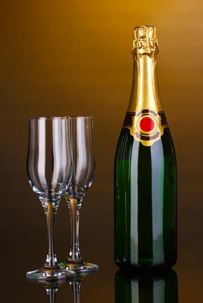 Flasche Champagner und Becher auf braunem Hintergrund — Stockfoto
