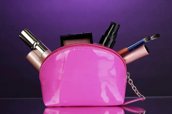 Make-up-Tasche mit Kosmetik und Pinseln auf violettem Hintergrund — Stockfoto