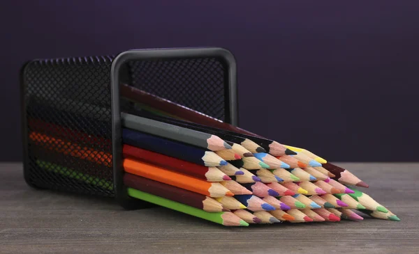 在紫罗兰色的背景上的木桌上的玻璃颜色铅笔 — 图库照片