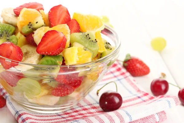 Ciotola di vetro con macedonia di frutta fresca e bacche su tavolo di legno bianco — Foto Stock