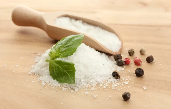 Salt with fresh basil, garlic and pepper on wooden table — Stock Photo, Image