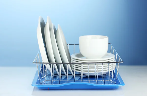 Pratos limpos em stand no fundo azul — Fotografia de Stock
