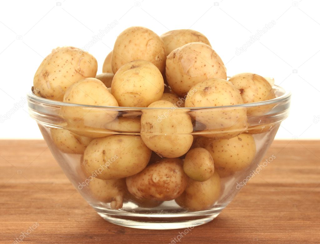 Young potatoes in a glass bowl on a table on white background