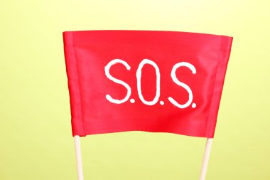 SOS signal written on red cloth on green background clipart