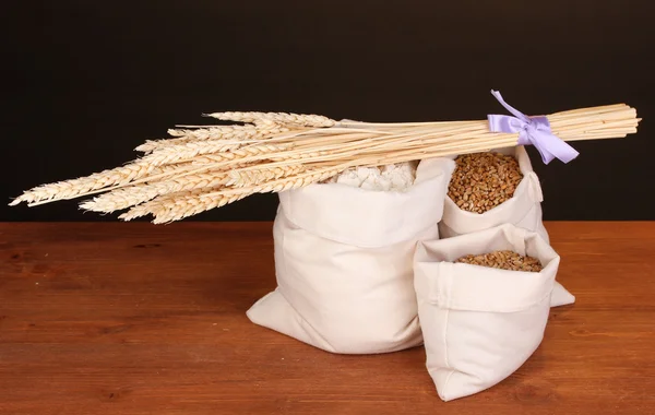 暗い背景に木製のテーブルの上の小麦粉と小麦の粒 — ストック写真