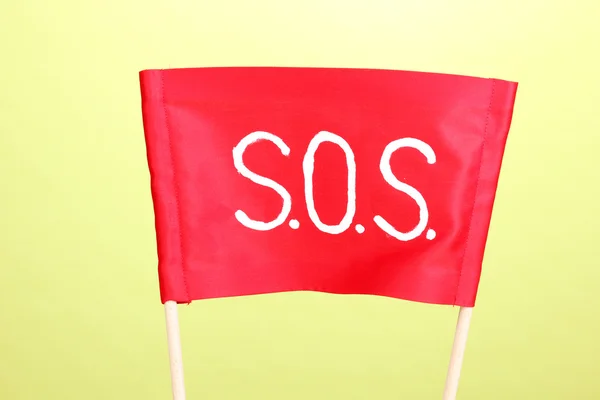 Σήμα SOS γραμμένο σε κόκκινο ύφασμα σε πράσινο φόντο — Φωτογραφία Αρχείου