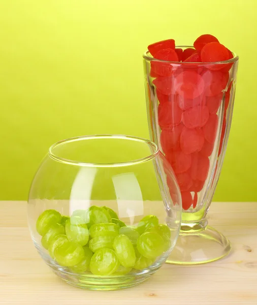 Kleur snoepjes in bril op houten tafel op groene achtergrond — Stockfoto