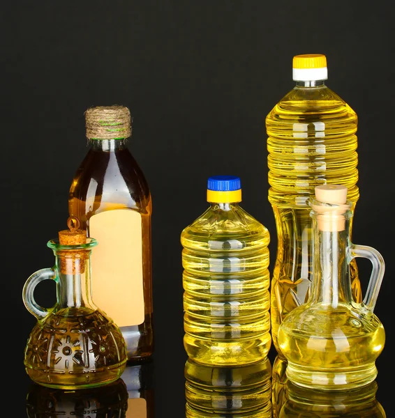 Olio di oliva e girasole nelle bottiglie e piccoli decanter isolati su fondo nero primo piano — Foto Stock