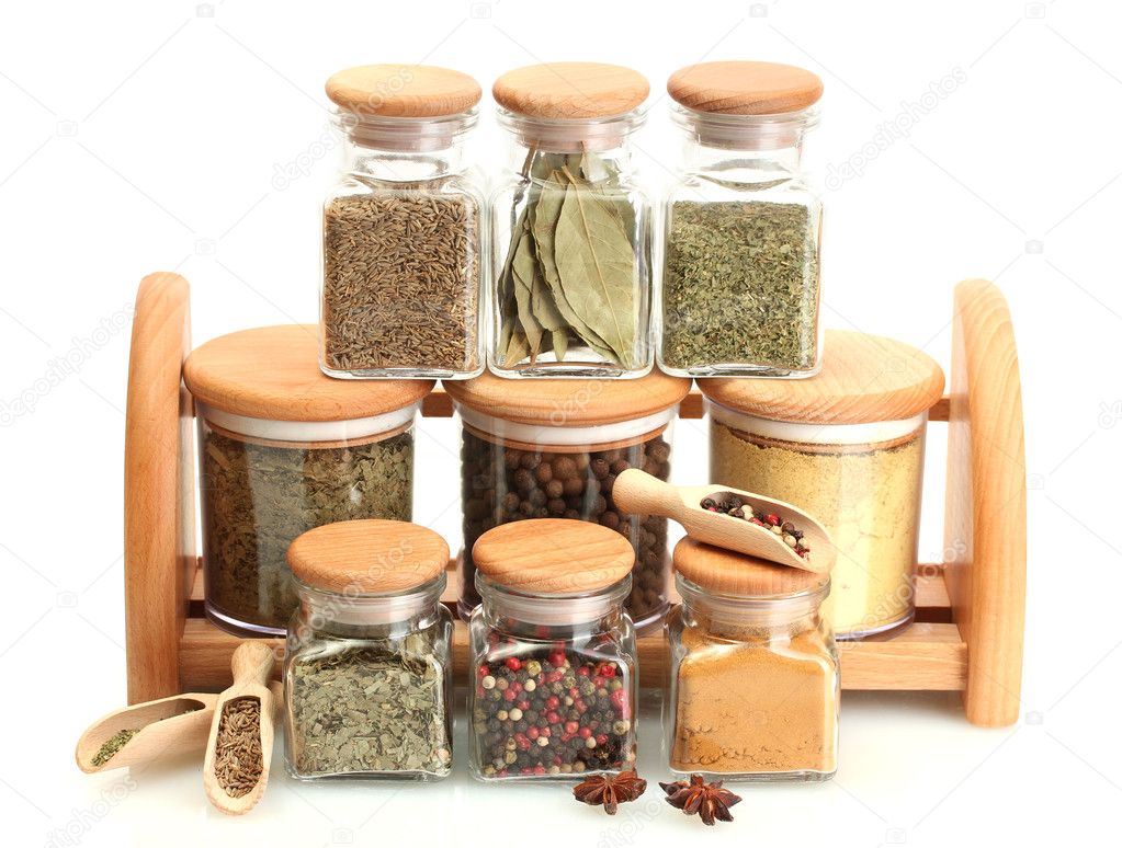Jars and wooden spoons on shelf with spices isolated on white