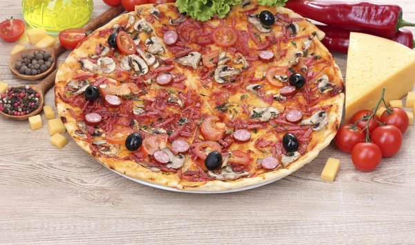 Delicious pizza and vegetables on wooden table — Stock Photo, Image