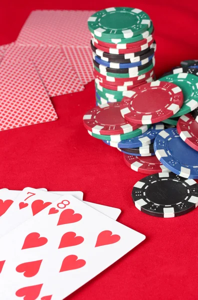 Jugar a las cartas con fichas de póquer en una mesa roja de póquer — Foto de Stock