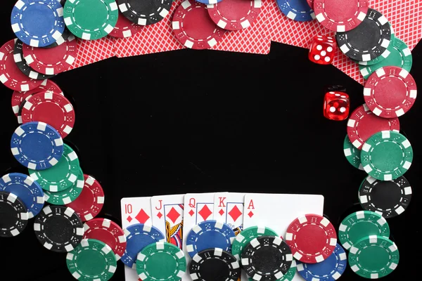 Frame made of playing cards and poker chips on black background close-up