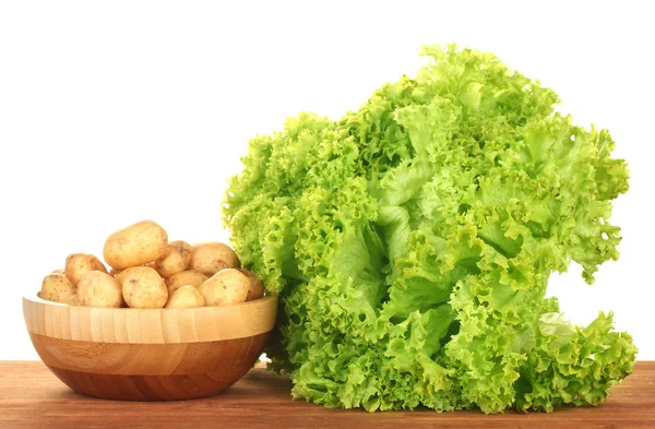 Young potatoes in a wooden bowl with lettuce on a table on white background — Stock Photo, Image