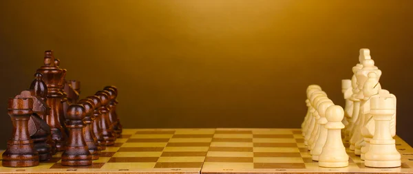 Schaakbord met schaakstukken op bruine achtergrond — Stockfoto