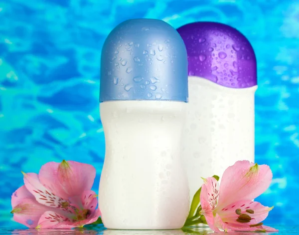 Desodorantes con flores sobre fondo azul marino —  Fotos de Stock