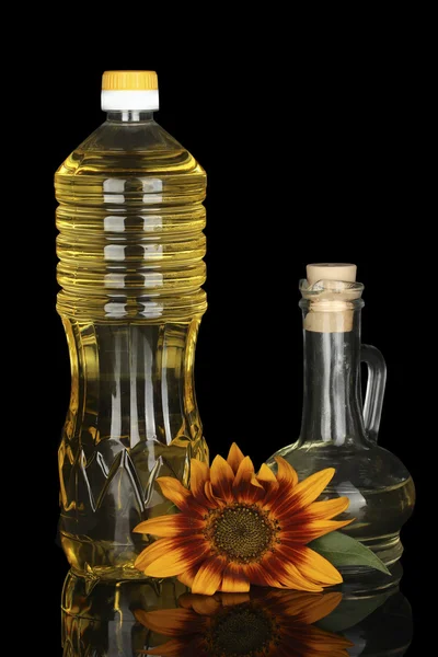 Olej słonecznikowy w plastikowej butelce i małe karafki na białym tle na czarnym tle — Zdjęcie stockowe