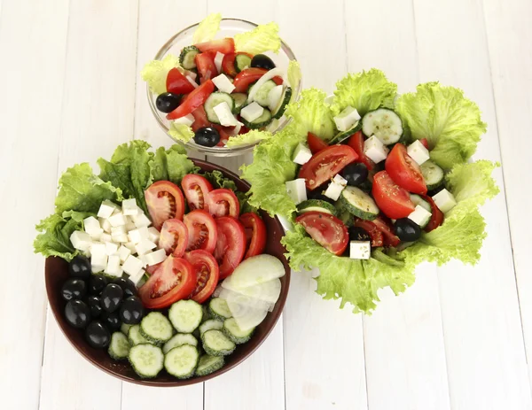 Három ízletes görög saláta fehér fa háttér — Stock Fotó
