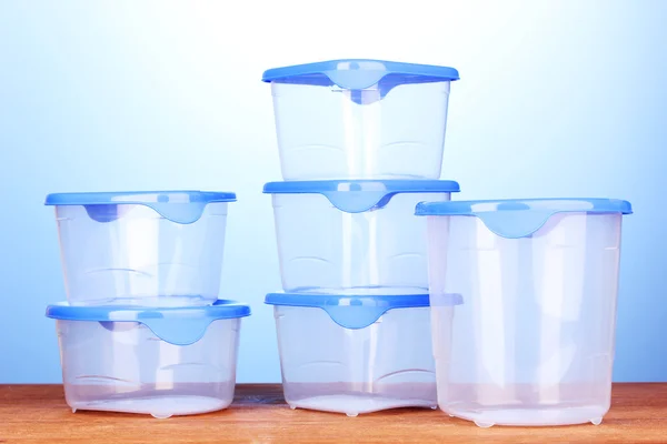 青色の背景に木製のテーブルの上の食品用プラスチック容器 — ストック写真