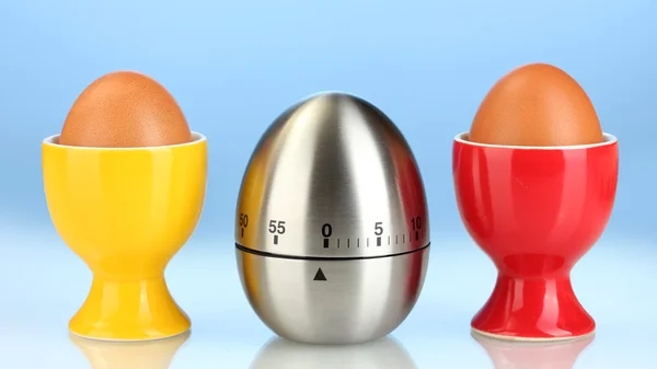 Temporizador de huevo y huevo en soporte de color sobre fondo azul —  Fotos de Stock