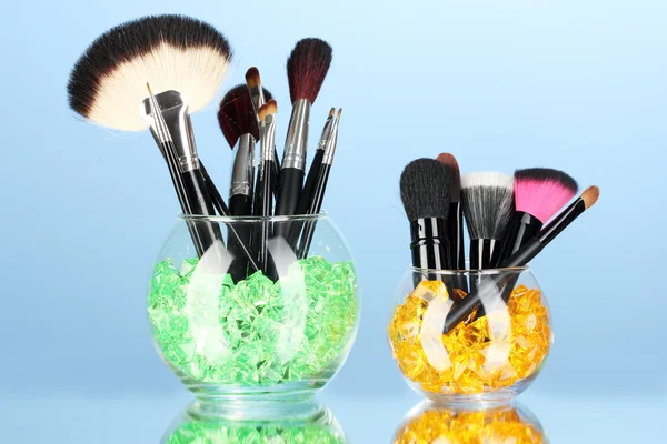 Make-up brushes in two bowls with stones on blue background — Stock Photo, Image