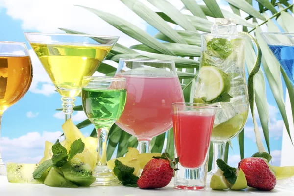 stock image Glasses of cocktails on table on blue sky background