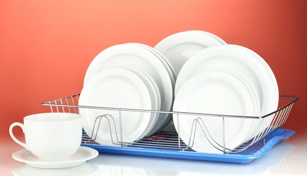 Clean dishes on stand on red background — Stock Photo, Image