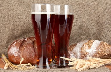 Two glasses of kvass with bread on canvas background close-up clipart