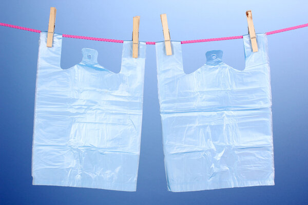 Целофановые мешки висят на веревке на синем фоне
