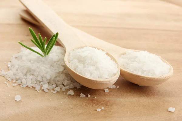 Sůl v lžíce s čerstvým rozmarýnem na dřevěné pozadí — Stock fotografie