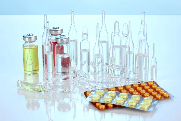 Tabletten en ampullen op blauwe achtergrond — Stockfoto