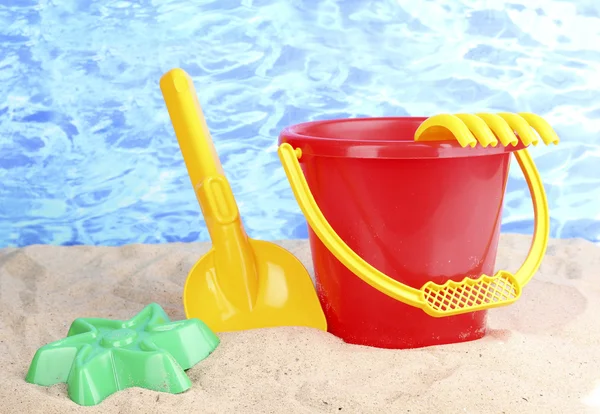 Dětské plážové hračky na písku na pozadí vody — Stock fotografie