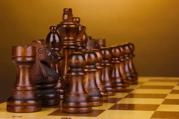 Σκακιέρα με τα κομμάτια του σκακιού σε καφέ φόντο — Φωτογραφία Αρχείου