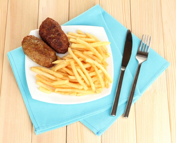 Batatas fritas com hambúrgueres no prato em fundo de madeira close-up — Fotografia de Stock