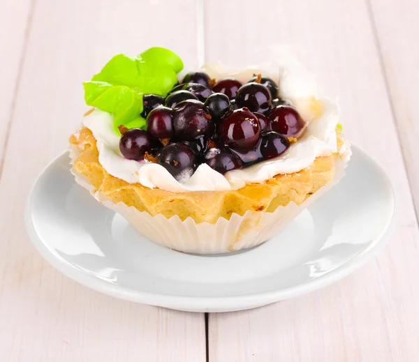 Süßer Kuchen mit Beeren auf Untertasse auf hölzernem Hintergrund — Stockfoto