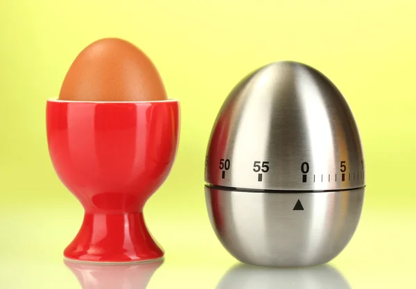 Temporizador de ovos e ovo em pé vermelho no fundo verde — Fotografia de Stock