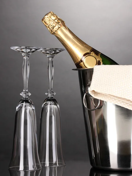 Champagne bottle in bucket with ice and glasses on grey background — Stock Photo, Image
