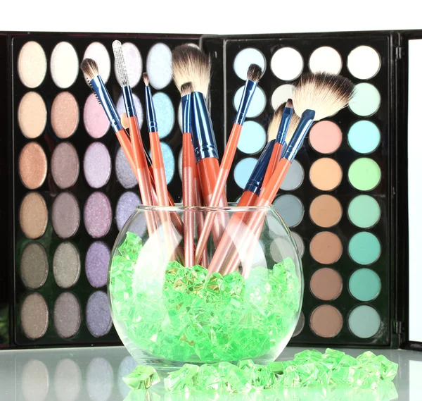 Make-up borstar i en skål med stenar på palett av skuggor bakgrund — Stockfoto