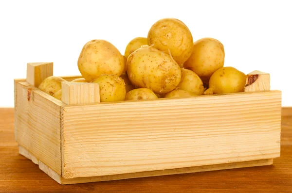 Young potatoes in a wooden box on a table on white background close-up — Stock Photo, Image