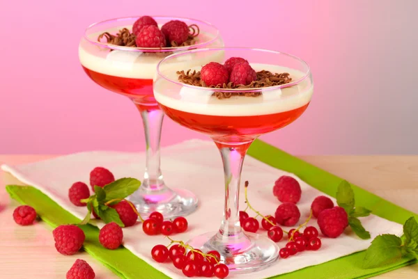 Jalea de frutas con bayas en vasos sobre mesa de madera sobre fondo rosa —  Fotos de Stock