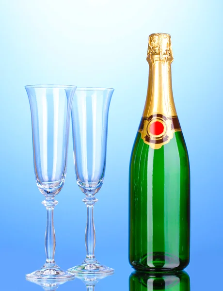 Garrafa de champanhe e taças sobre fundo azul — Fotografia de Stock