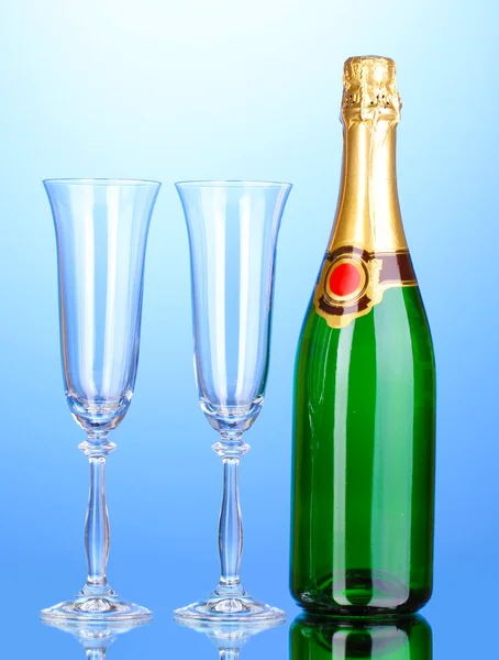 Láhev šampaňského a pohárů na modrém pozadí — Stock fotografie