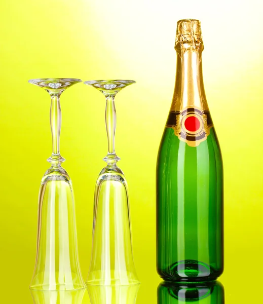 Fles champagne en bekers op groene achtergrond — Stockfoto
