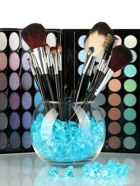 Make-up brushes in a bowl with stones on palette of shadows background — Stock Photo, Image