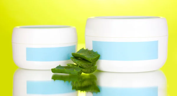 Jars of cream with aloe vera on green background — Stock Photo, Image