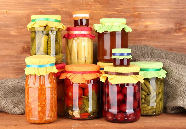 Jars with canned vegetables and fruit on wooden background close-up — Stock Photo, Image